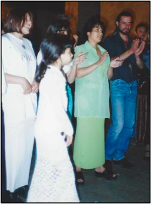 Mother (in green) sings and claps, while her daughters think about dancing